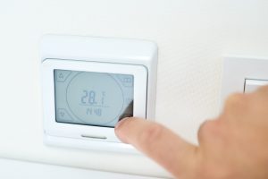 men hand setting temperature on the underfloor heating control panel scaled